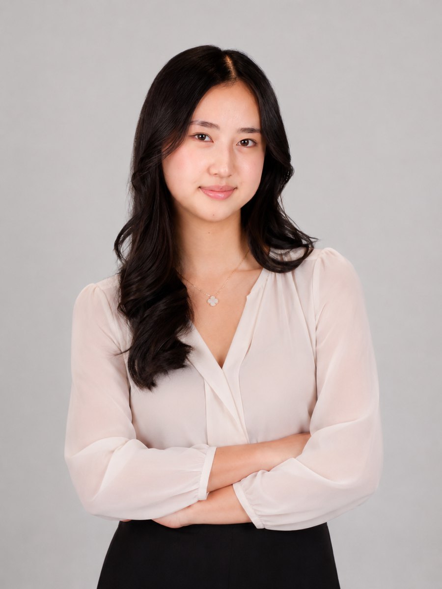 Kimi in a cream blouse, arms crossed, against a grey studio backdrop